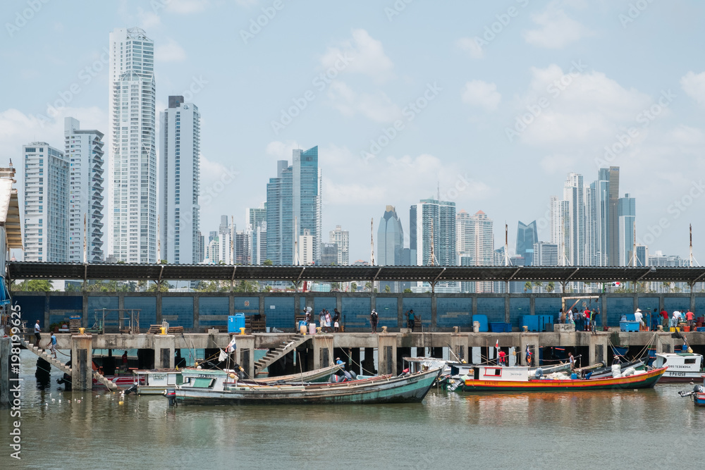 Fishermen and boats on fish market / harbour with city skyline, Panama City