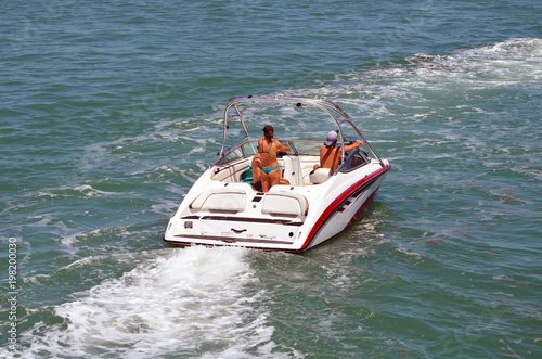 Two guys and a girl in a bikini pleasure cruising on a Sunday afternoon on the Florida Intra-coastal Waterway off Miami Beach.