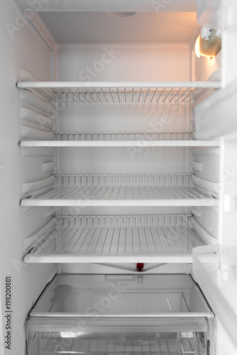 Open empty white refrigerator close-up.