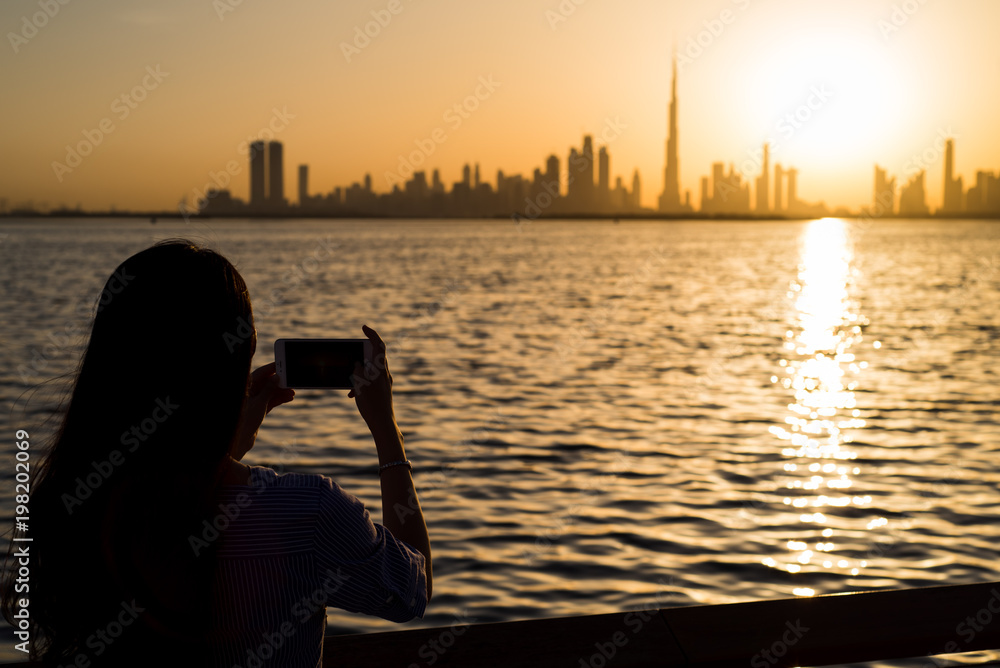 Woman taking photo of Dubai at sunset