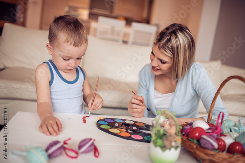 Mother and her son painting eggs
