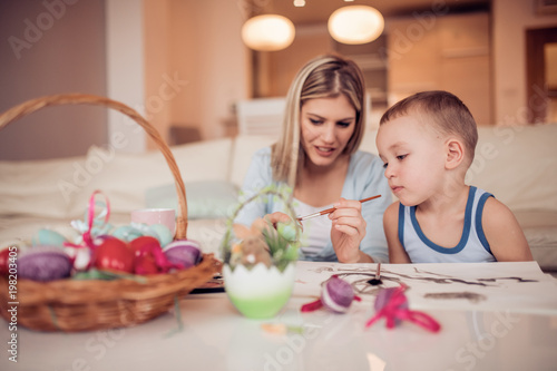 Portrait of little boy and mother coloring eggs for Easter