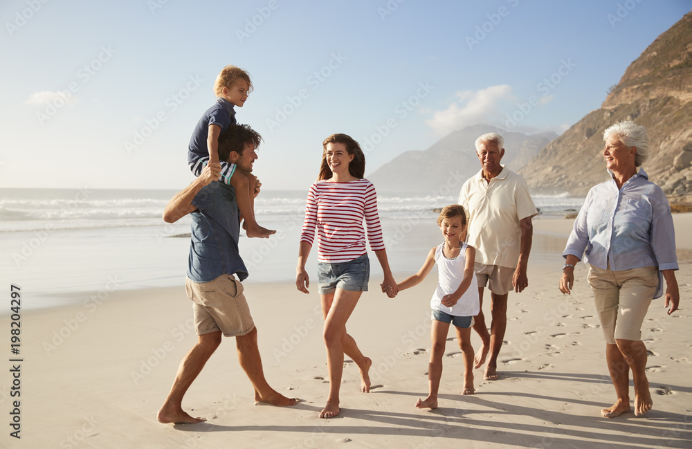 Multi Generation Family On Vacation Walking Along Beach Together Multi Generation Family On Vacation Walking Along Beach Together