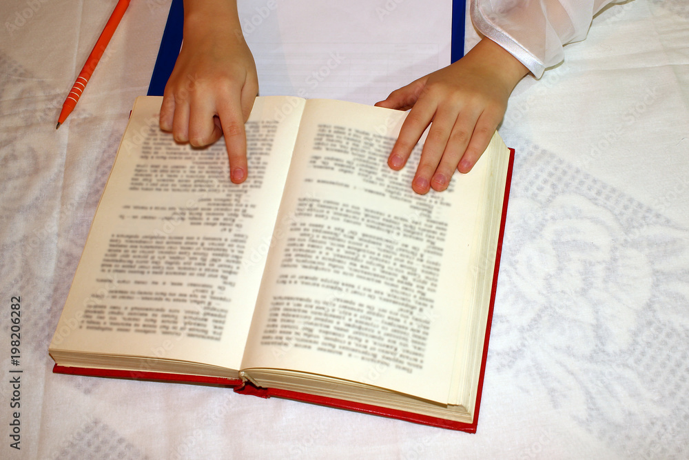 Naklejka premium Female hands holding a big book, on a white table, reading,