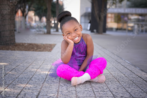 Little girl wearing tutu and sitting on sidewalk photo