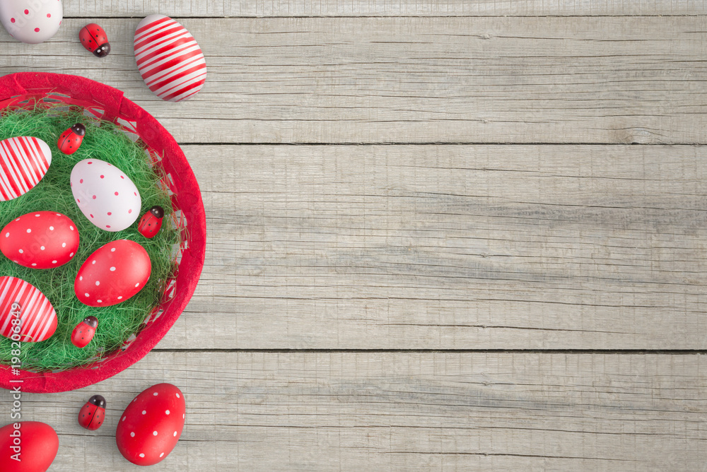 Easter background with red colorful eggs, basket and ladybug decorations. Wooden table. Flat lay. Easter background with red colorful eggs, basket and ladybug decorations. Wooden table. Flat lay.