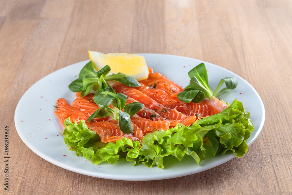 salted salmon with a slice of lemon on a sheet of green salad salted salmon with a slice of lemon on a sheet of green salad