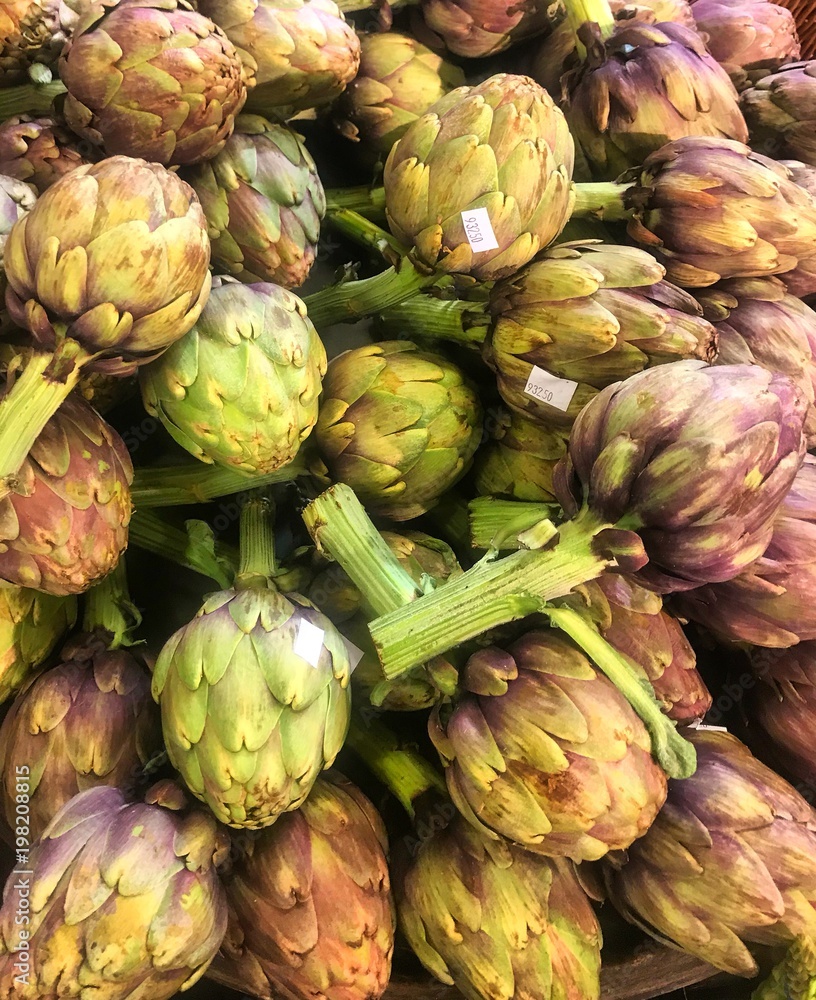 Obraz premium Pile of beautiful green and purple artichokes, fresh vegetables at organic market stall, premium produce, homegrown globe artichokes, french artichokes in a heap