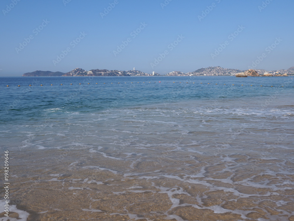 Beauty panorama of Pacific Ocean waves on sandy beach at bay of ACAPULCO city in Mexico