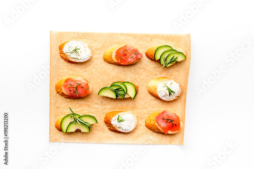 Healthy lunch with mini sandwiches cheese, fish and avocado on white background top view space for text