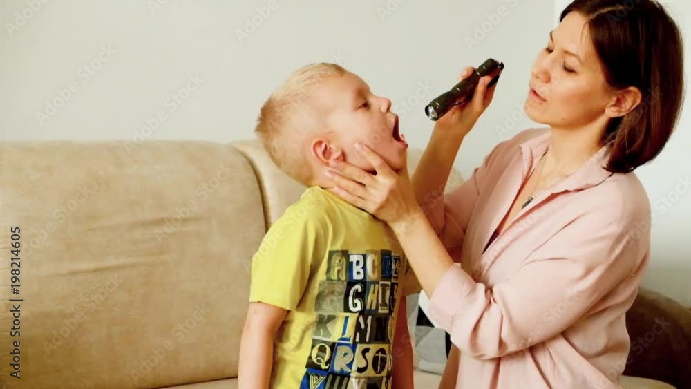 Mother having throat examined checking little boy at home Mother having throat examined checking little boy at home
