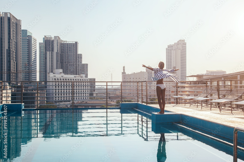 Obraz premium Kobieta stojąca w basenie na dachu