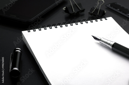 black pen pen lies on a white wicker book in the background phone, ruler, paperclips. business