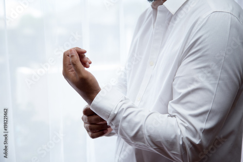 Man Groom or businessman buttons shirt a man in a white shirt morning wedding preparation.