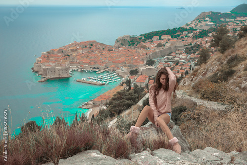 Brunette Girl tourist visiting mountain viewpoint sightseeing in Dubrovnik, Croatia. Woman traveller in front on famous travel destination. Free brunette enjoying vacation.