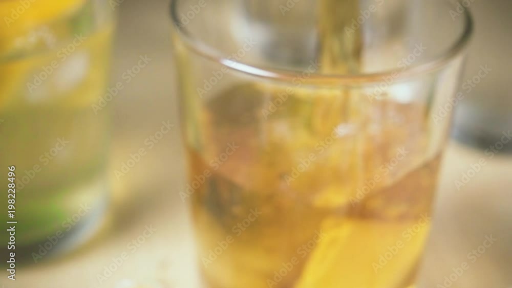 Slow motion blurred background the camera is moving and the tea is poured into a glass with ice on the focus Slow motion blurred background the camera is moving and the tea is poured into a glass with ice on the focus