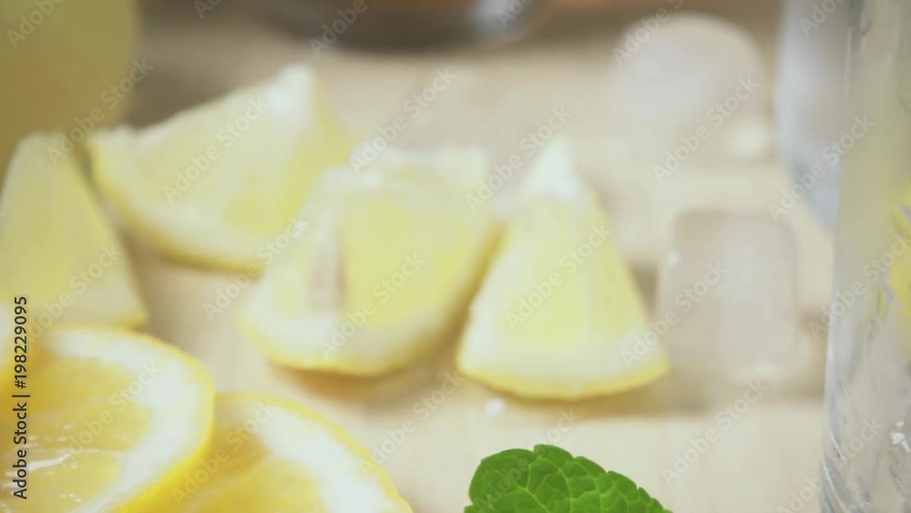 Slow motion the tea is poured into a glass with ice and mint and the camera moves from the lemon to the glass Slow motion the tea is poured into a glass with ice and mint and the camera moves from the lemon to the glass