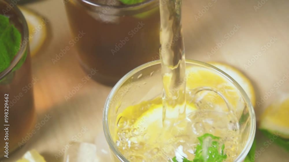 Slow motion tea with ice and mint in a glass and movement of the camera on a stream of water in a glass with ice and mint. Slow motion tea with ice and mint in a glass and movement of the camera on a stream of water in a glass with ice and mint.