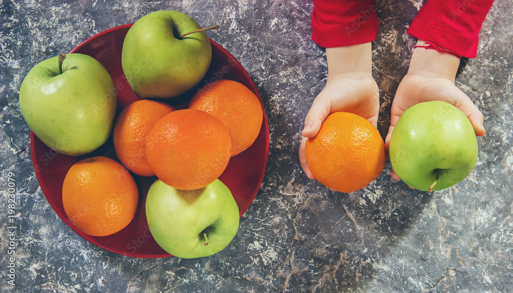 apples and oranges in the hands of a child. Selective focus. StockFoto