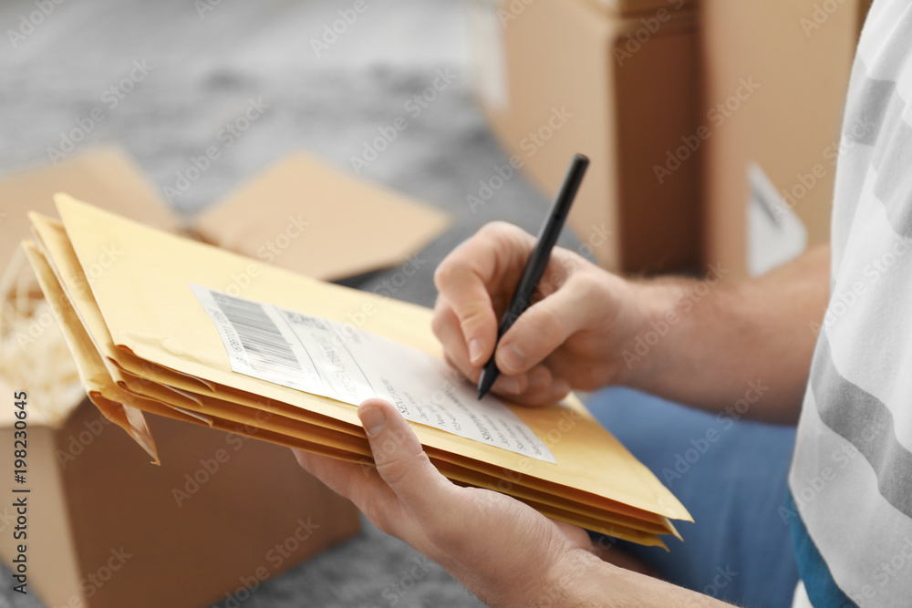 Young man preparing parcel envelopes for shipment to client at home, closeup Young man preparing parcel envelopes for shipment to client at home, closeup
