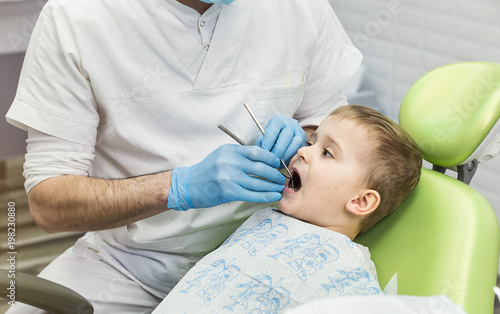 Dentist examining little boy's teeth in clinic. Dental problem.