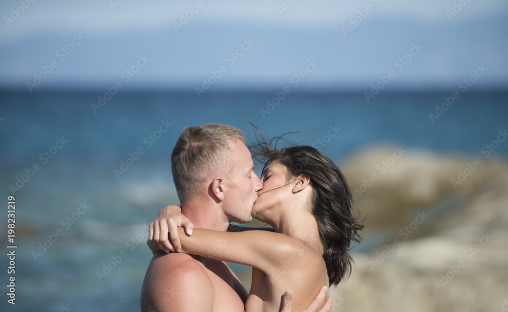 Couple in love kissing on seafront. Happy family spend time together, hug and kiss, sea surface background. Honeymoon concept. Sensual nude attractive couple on passionate faces. Couple in love kissing on seafront. Happy family spend time together, hug and kiss, sea surface background. Honeymoon concept. Sensual nude attractive couple on passionate faces.