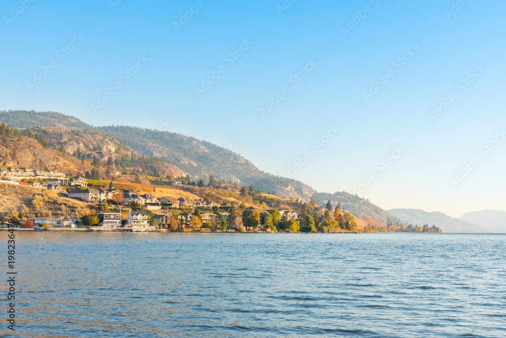 Waterfront homes and mountains on lake with blue sky and warm light from evening sunshine in autumn