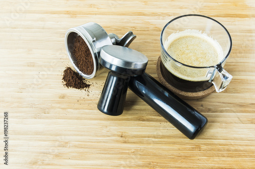 cup of espresso on wooden board with ground coffee