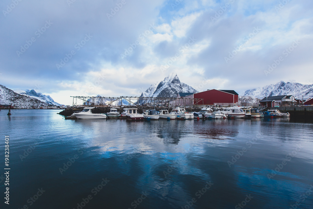 Beautiful super wide-angle winter snowy view of Reine, Norway, Lofoten Islands, with skyline, mountains, famous fishing village with red fishing cabins, Moskenesoya, Nordland