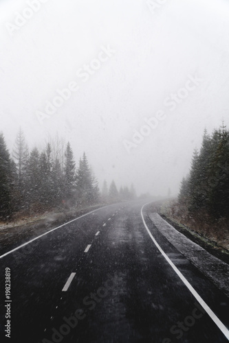Blurry dangerous car overtaking on highway at heavy snowy conditions. traffic situation, marks, Problems, vertical photo