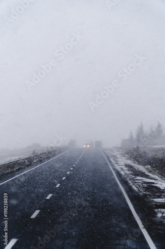 Blurry dangerous car overtaking on highway at heavy snowy conditions. traffic situation  marks  Problems  vertical photo