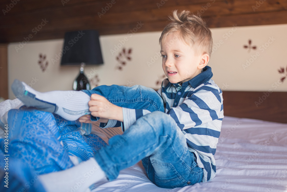 Five years old boy dresses his socks in the morning on the bed Five years old boy dresses his socks in the morning on the bed