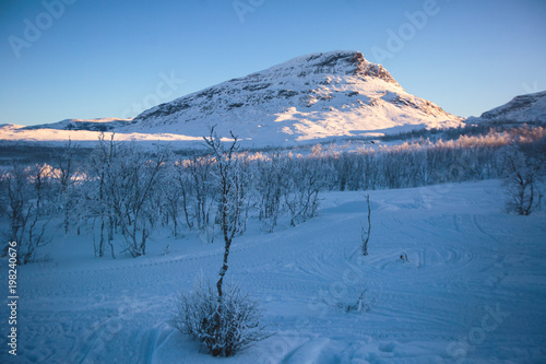 Beautiful cold mountain view of ski resort in Lapland, sunny winter day with slope, piste and ski lift photo