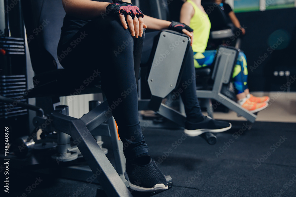Leg training in hip muscle simulator. Girls train glutes of fitness, pushing legs in block. Leg training in hip muscle simulator. Girls train glutes of fitness, pushing legs in block.