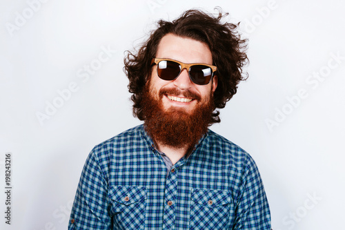 Portrait of young bearded hipster man wearing sunglasses. Happy concept. Smiling man with beard. Curly hair.