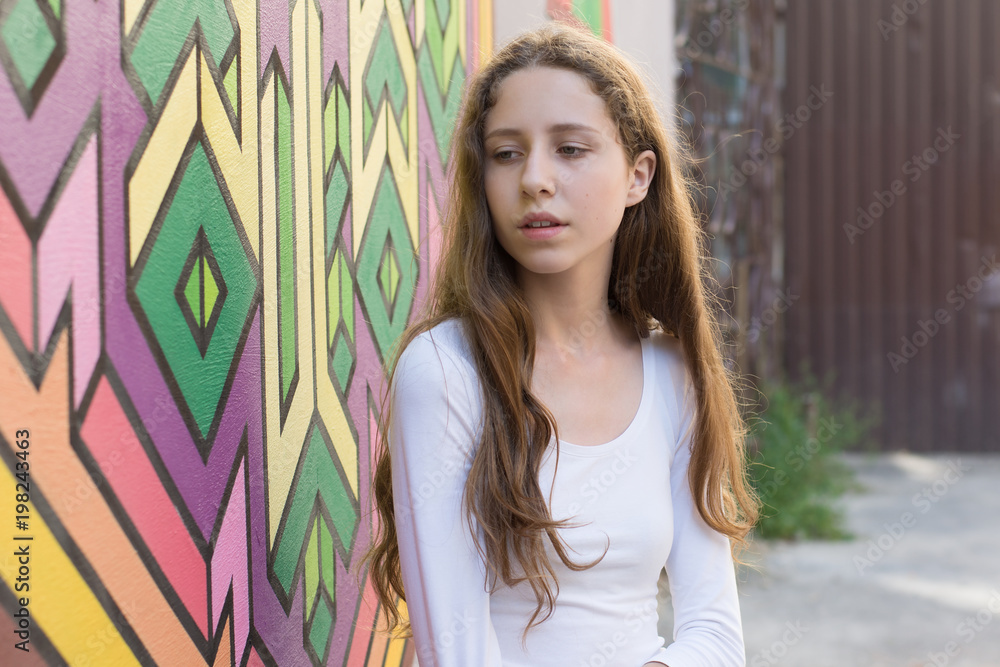 Fototapeta premium Portrait of a young beautiful girl against the art wall background.