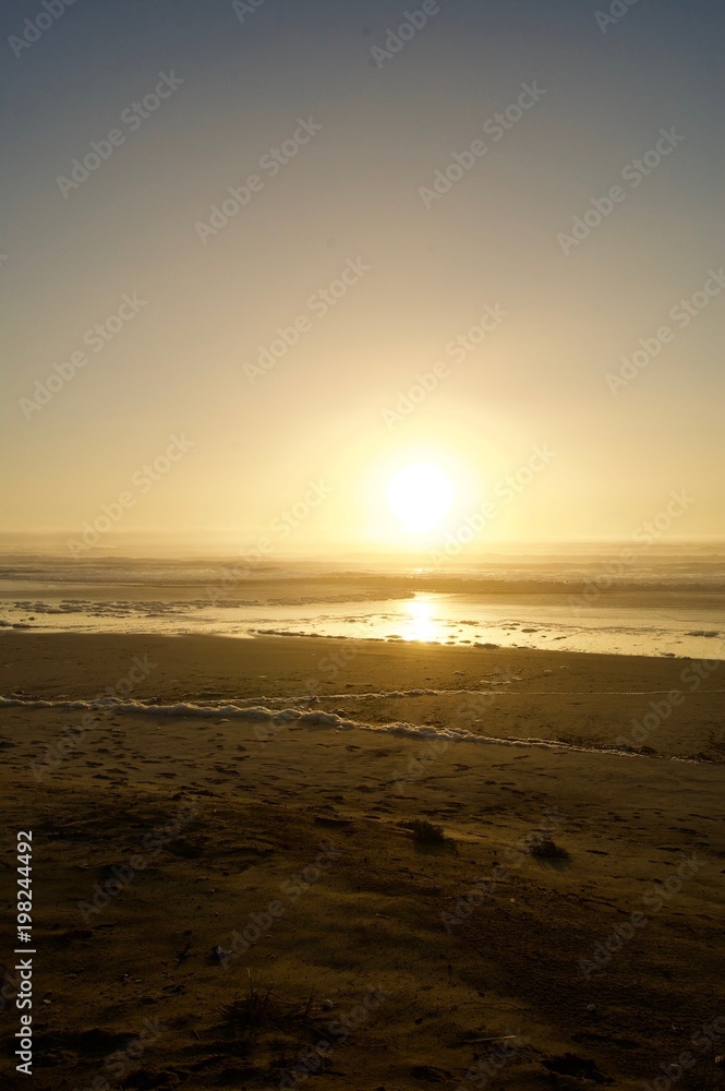 Picturesque idyllic sunset at the beach in California (USA) with bubbly waves, a sand beach and orange light creates a tranquil, dreamy and romantic scenery
