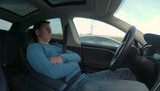 Man relaxes while his high tech self driving car navigates through rush hour
