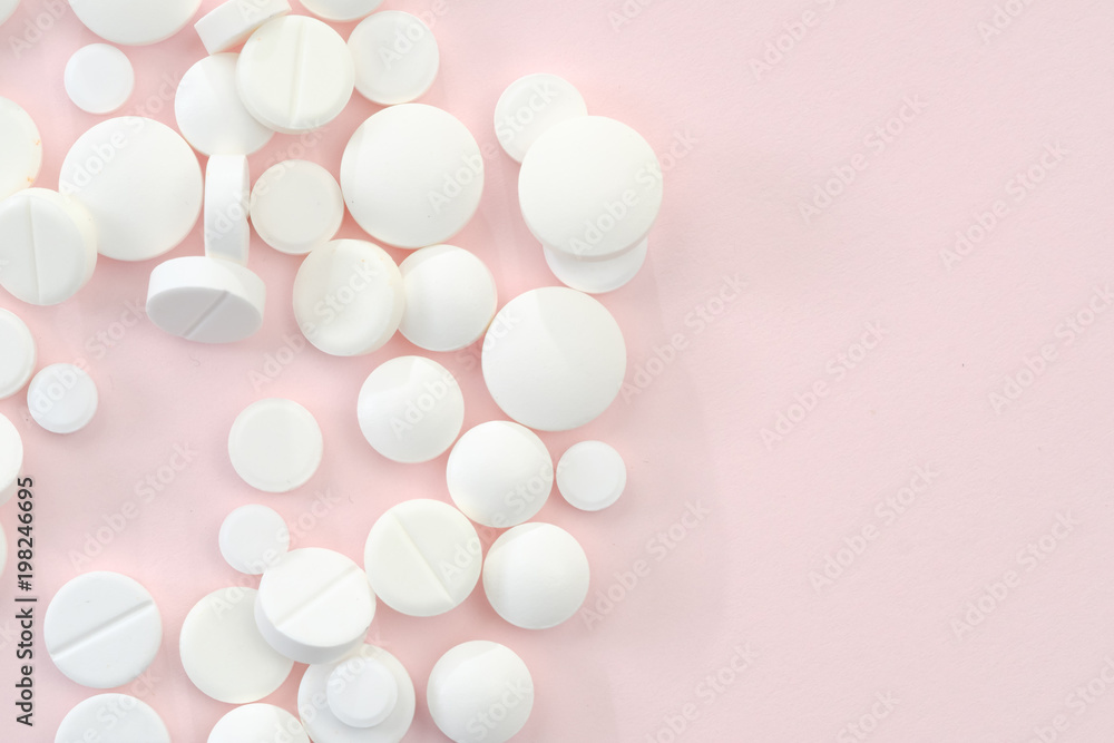 Heap of white pills on pink background
