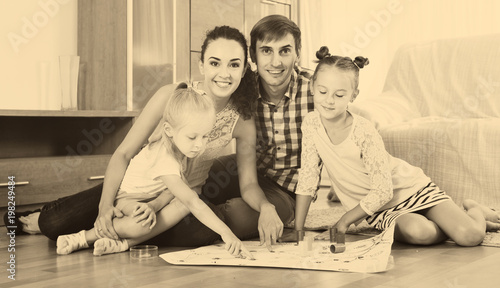 girls playing with parents at board game on floor