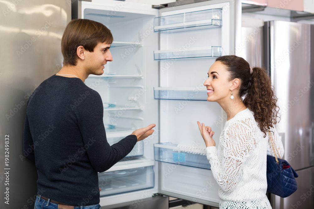 family couple choosing new refrigerator in hypermarket