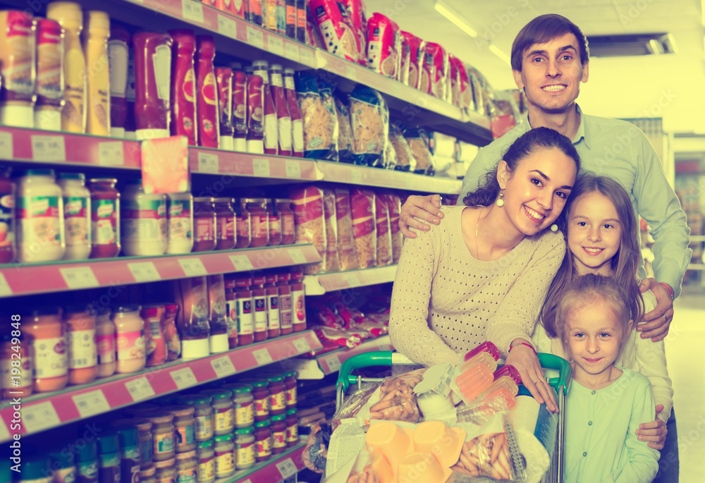 Couple with children buying food in hypermarket.