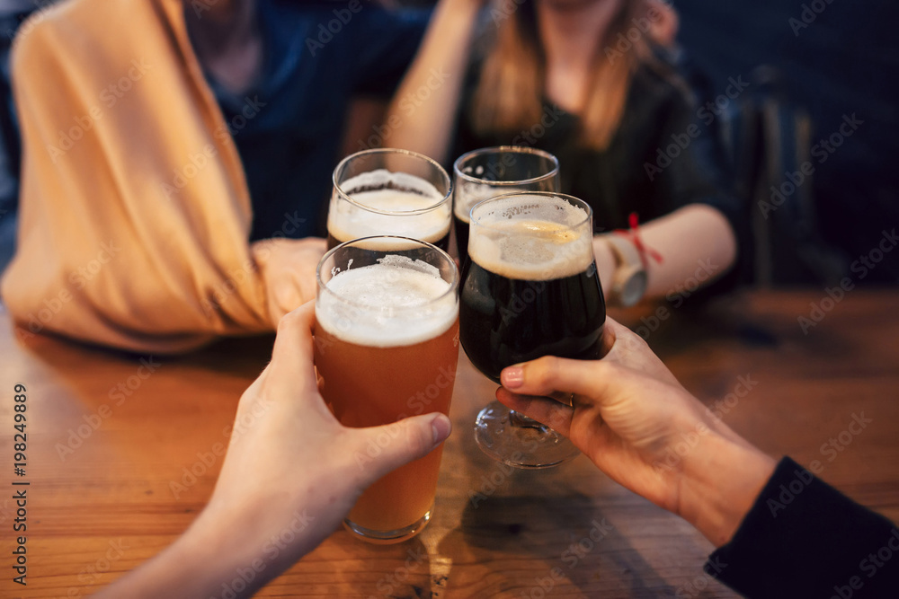 hands of people holding beer and cheering in brewery pub. people toasting with delicious beer in bar. friends drinking and enjoying a beer. leisure and friendship concept hands of people holding beer and cheering in brewery pub. people toasting with delicious beer in bar. friends drinking and enjoying a beer. leisure and friendship concept