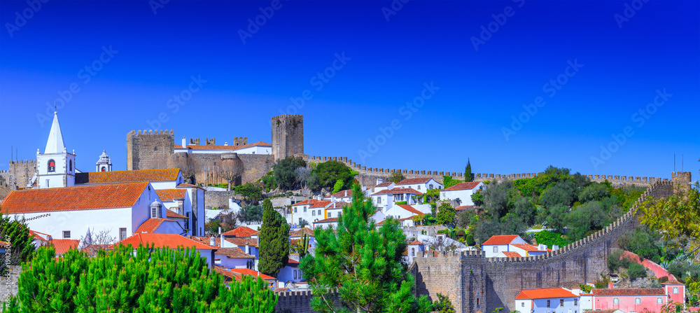 Obraz premium Panoramic view of the beautiful medieval historic center village of Obidos and Castle of Obidos. Wonderful romantic afternoon landscape at sunny weather. District of Leiria, in the centre of Portugal.