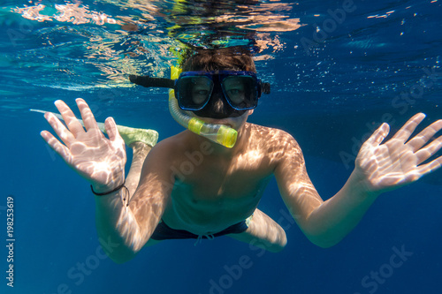 Boy in swimming mask dive in Red sea near yacht