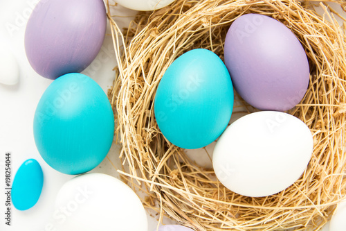 colored blue and purple Easter eggs in nest on wooden background, selective focus image. Happy Easter card 