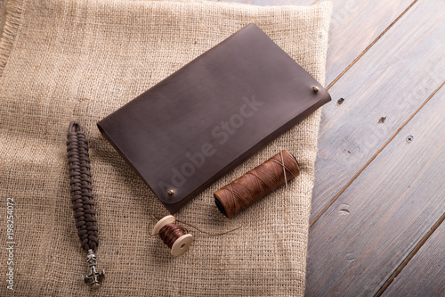 leather dark brown purse on a dark wooden background, with a thread and a needle. photo