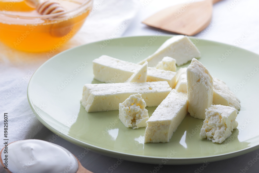 Cheese, honey and sour cream, feta in green plate, soft cheese on white background, wooden spoon with sour cream, French breakfast, blue napkin, honey in glass dishes, art