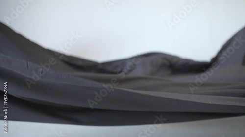 Black Cloth waving on a white background in super slow motion. Abstract visual of black cloth waving around.