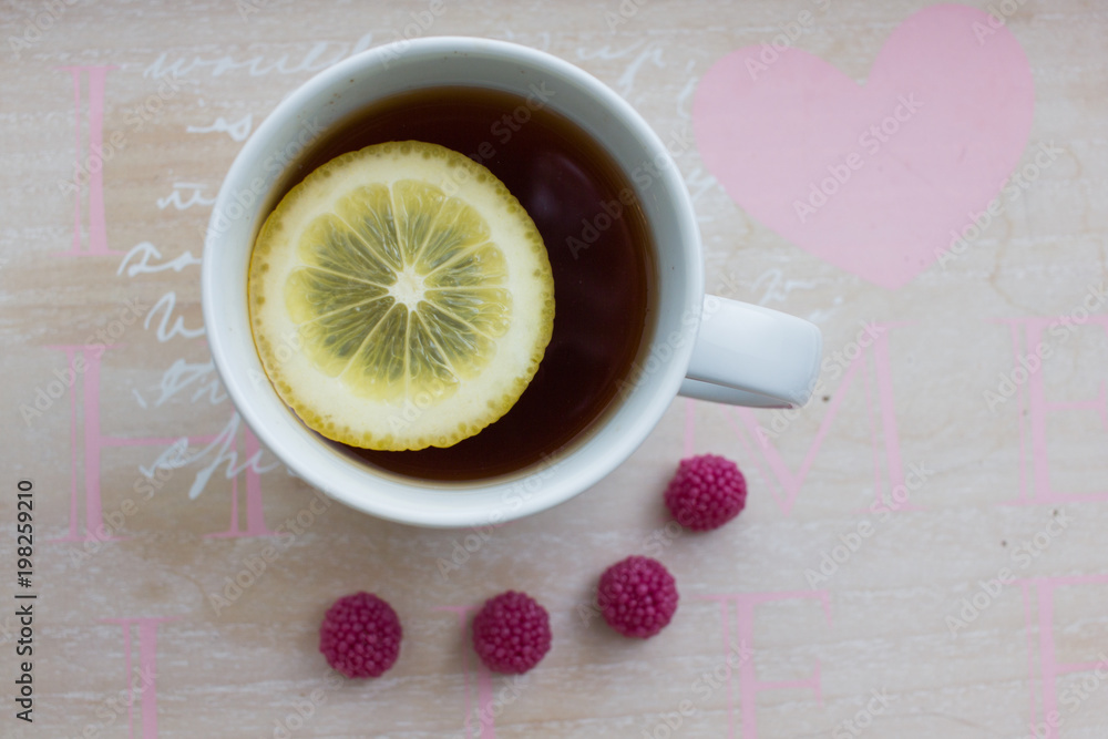 Cup of tea with lemon and raspberry sweets Cup of tea with lemon and raspberry sweets